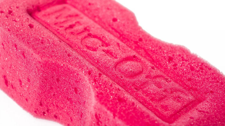 Närbild av Muc-Off Expanding Microcell Sponge Pink med präglad logotyp och mjuk struktur för effektiv rengöring.